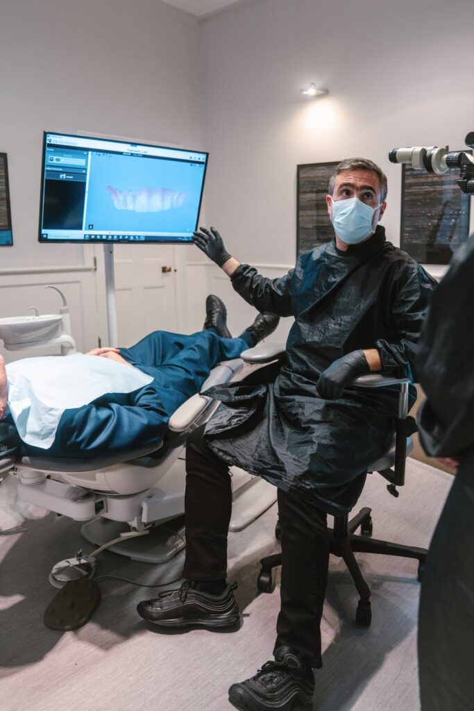 David Selouk mid procedure. A computer screen shows a photograph of teeth in the background