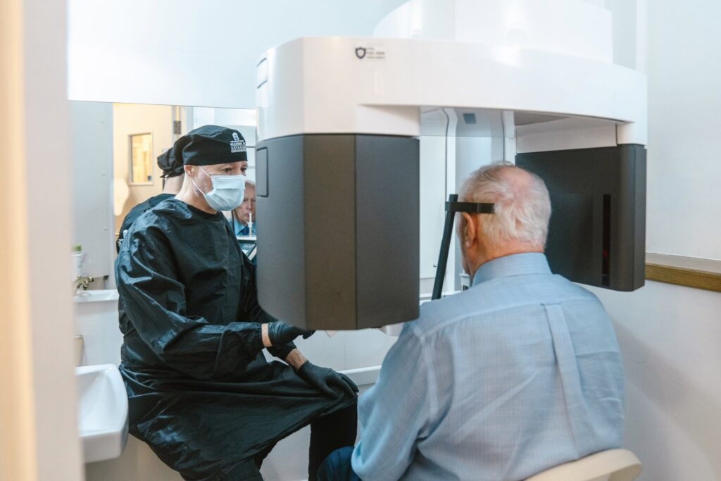 Richard Kahan taking his male patient for an x-ray. Male patient sitting inside x-ray machine