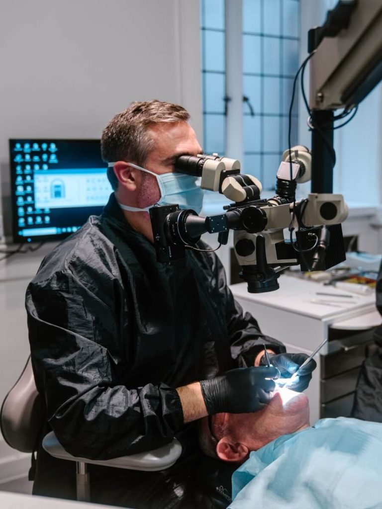 David Selouk looking through a dental microscope whilst checking a male patients teeth