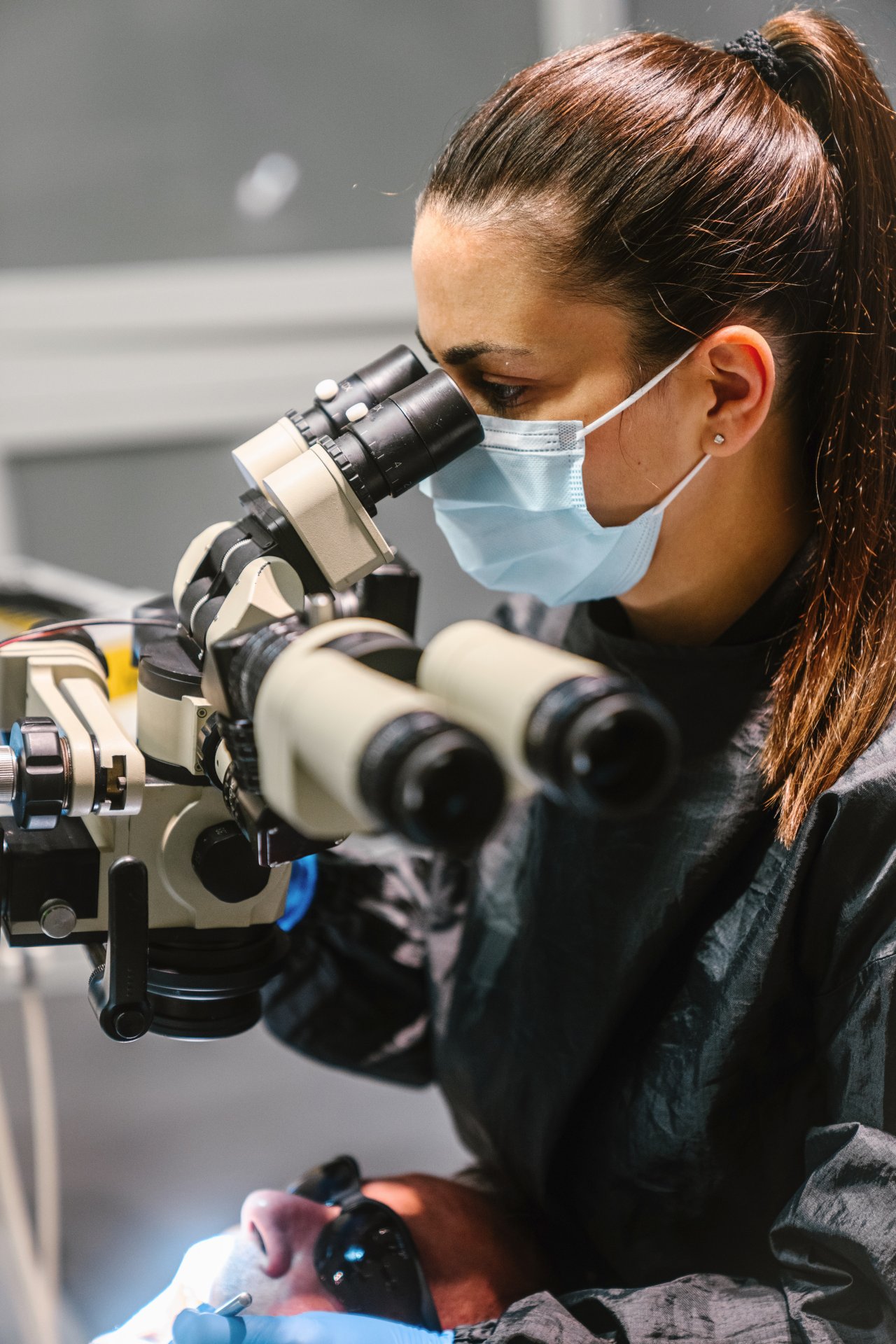 Female endodontist looking through a dental microscope
