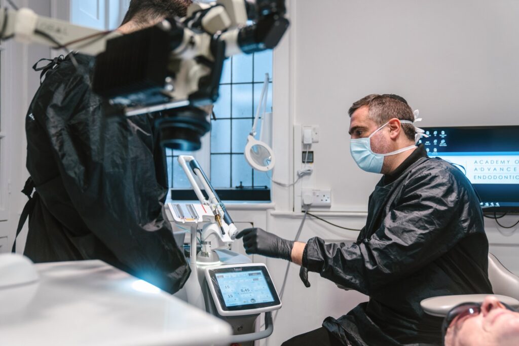 David Selouk mid procedure speaking to male assistant about dental equipment